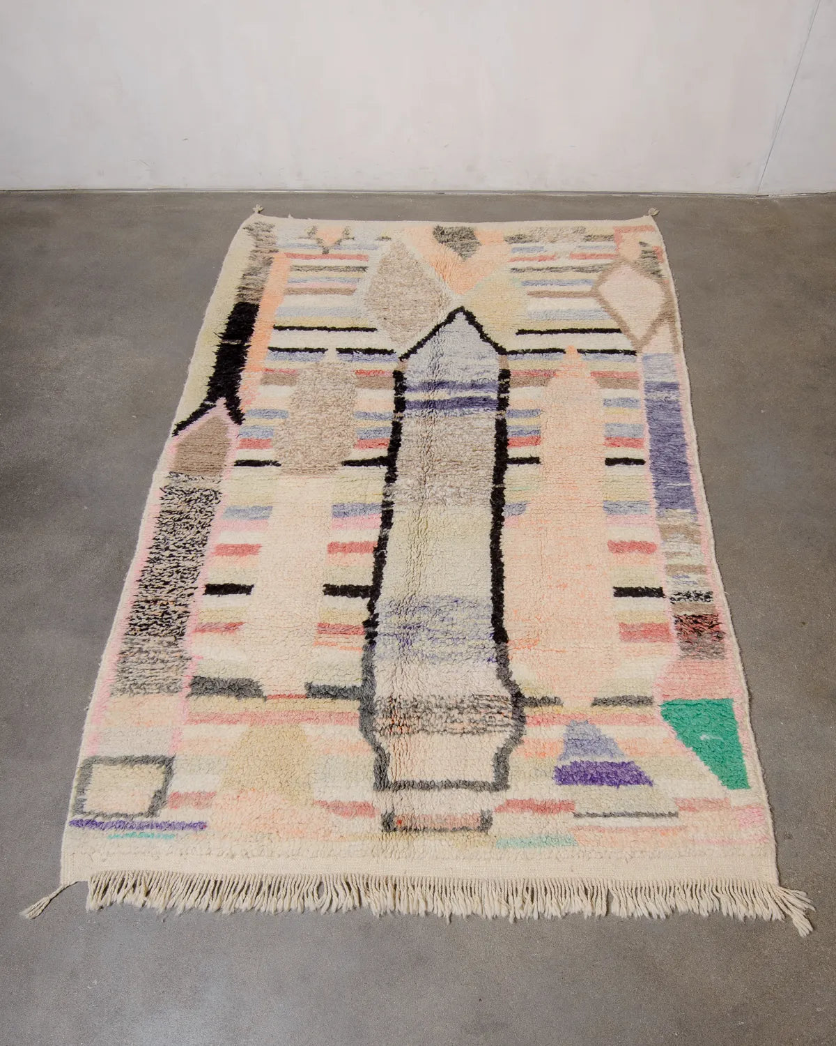 Berberlin vintage Berber rug in shades of soft brown, cream, orange, yellow and purple, laying flat on cement floor.